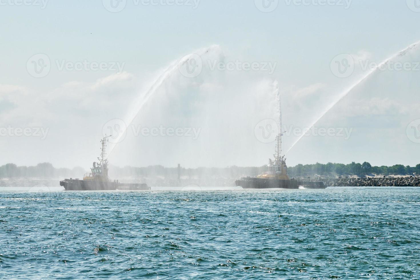 Schlepper, die Wasserstrahlen sprühen, Wasserwerfer zur Brandbekämpfung demonstrieren, Löschboote, die Schaum sprühen foto