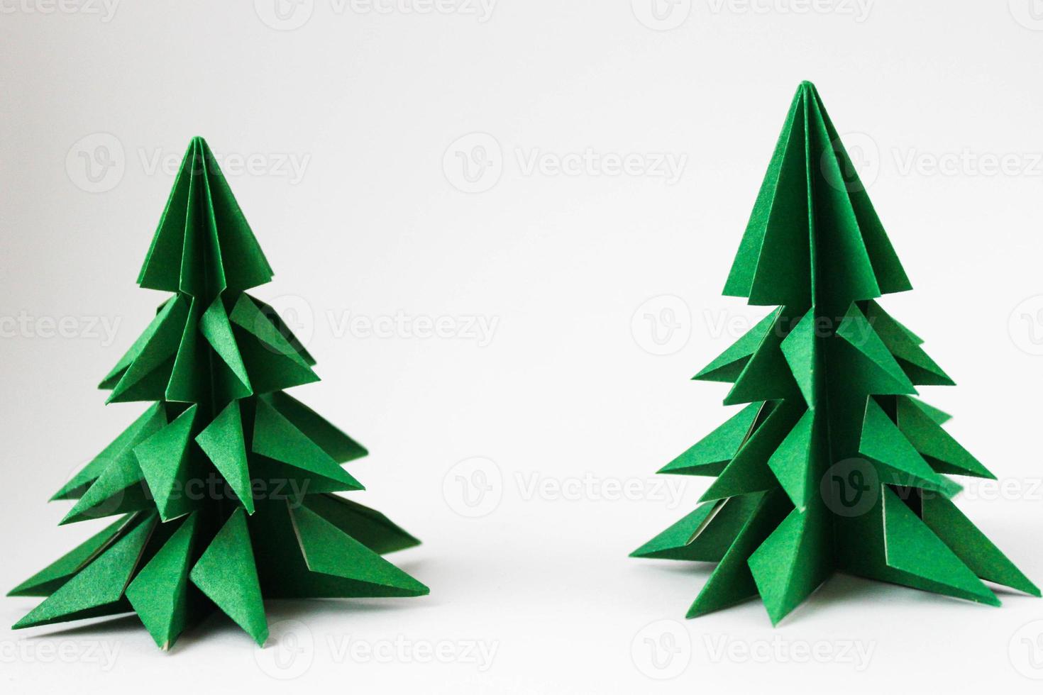 zwei grüne Origami-Weihnachtsbäume auf weißem Hintergrund. foto