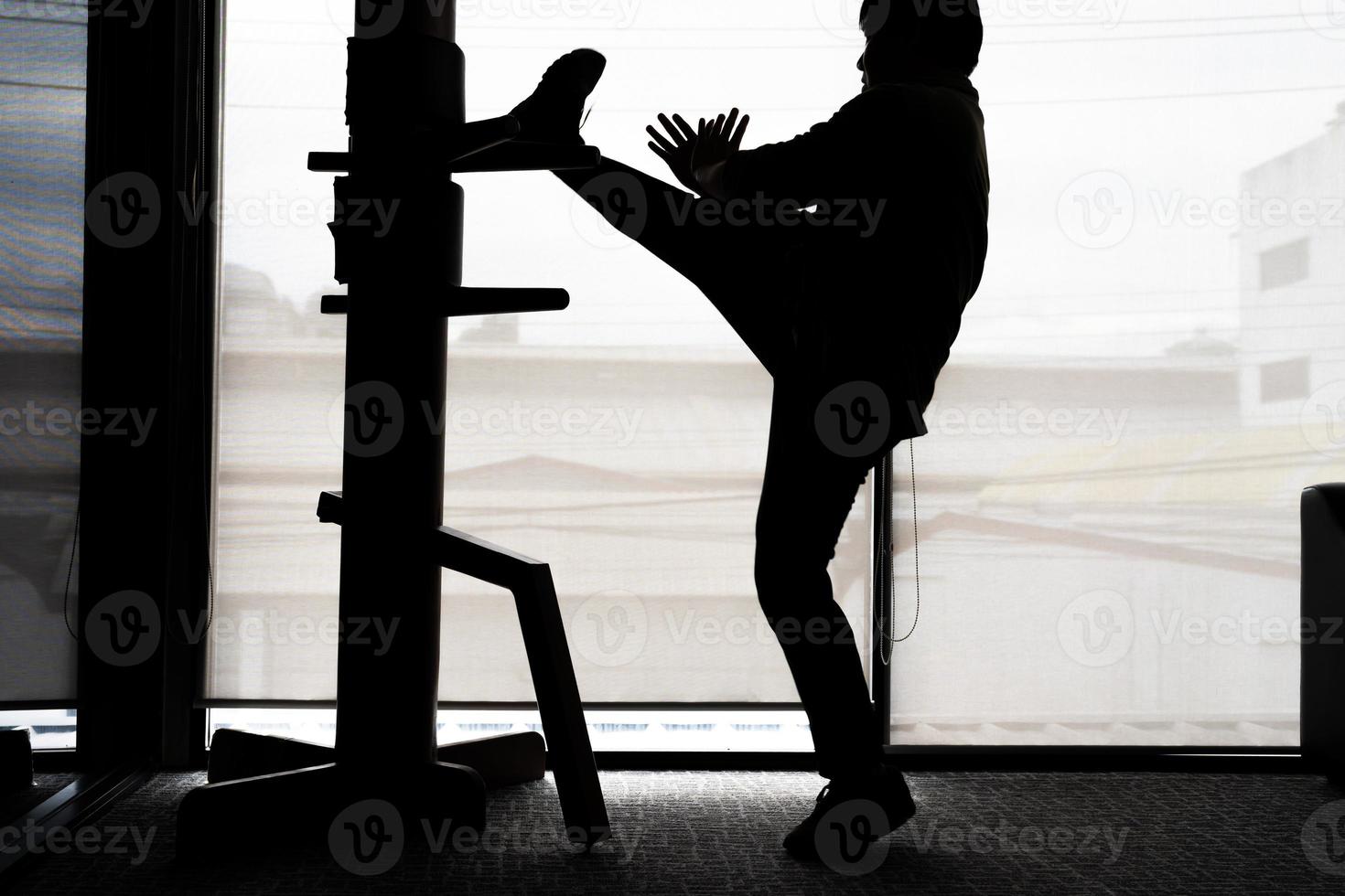 Silhouette eines Fighter Wing Chun und einer Holzpuppe auf einem Hintergrund. Wing Chun Kung Fu Selbstverteidigung foto