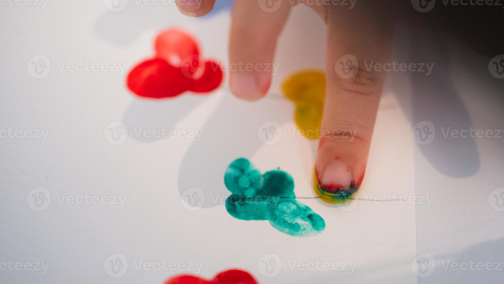 Die kleinen Finger der Kinder schaffen Kunst mit Wasserfarben. Kind tauchte seinen Finger in Farbe und klebte ihn auf weißes Papier seiner Fantasie. kinder hobbys. foto