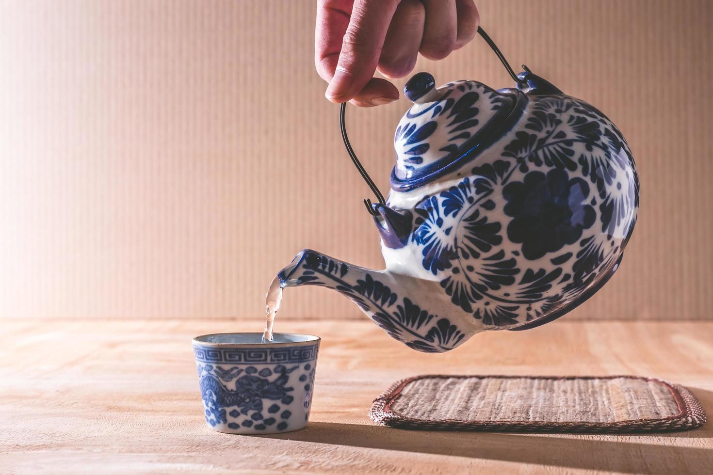Nahaufnahme der männlichen Hand, die Tee aus der chinesischen Teekanne gießt foto
