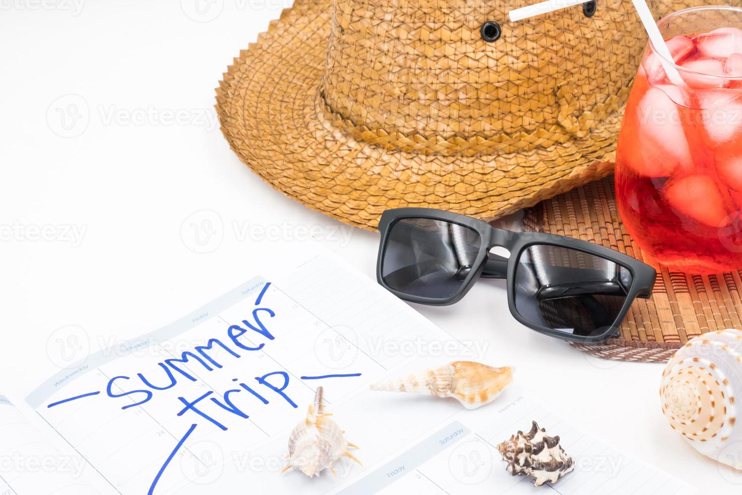 Hut mit Sonnenbrille, rotem Cocktail, Kalender und Muscheln auf weißem Hintergrund, Sommerferienkonzept foto