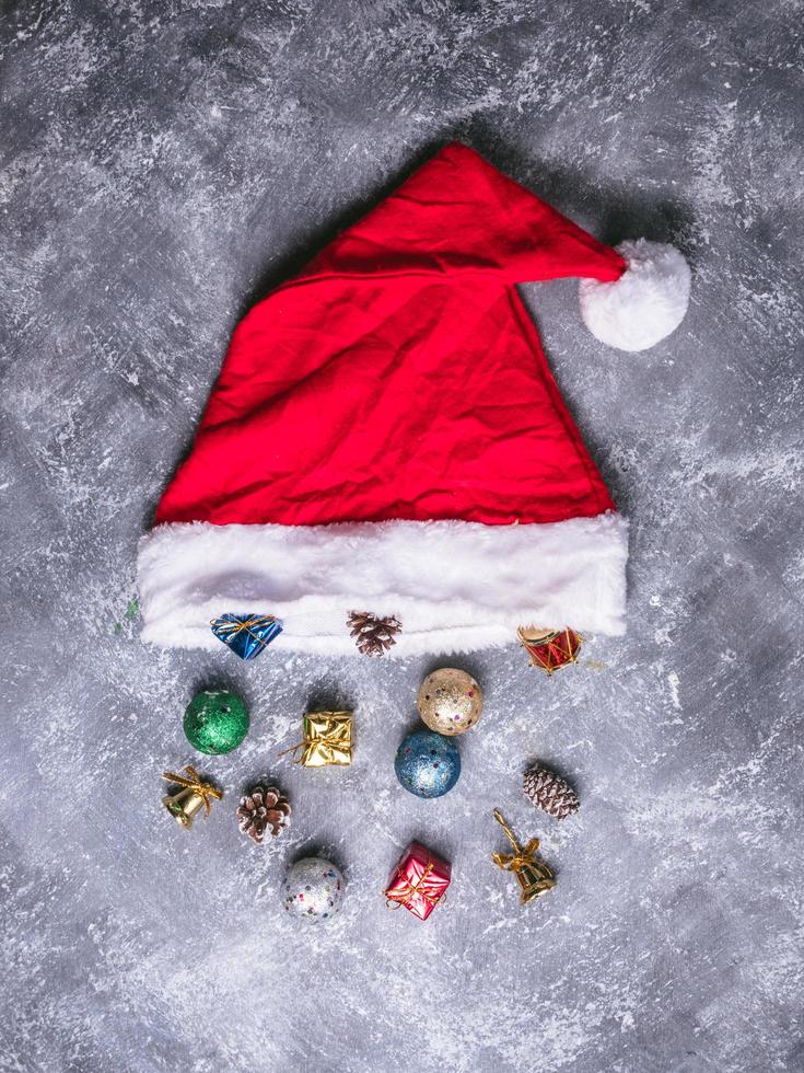 Draufsicht der Weihnachtsmütze mit Weihnachtsdekoration auf grauem Grunge-Hintergrund. foto