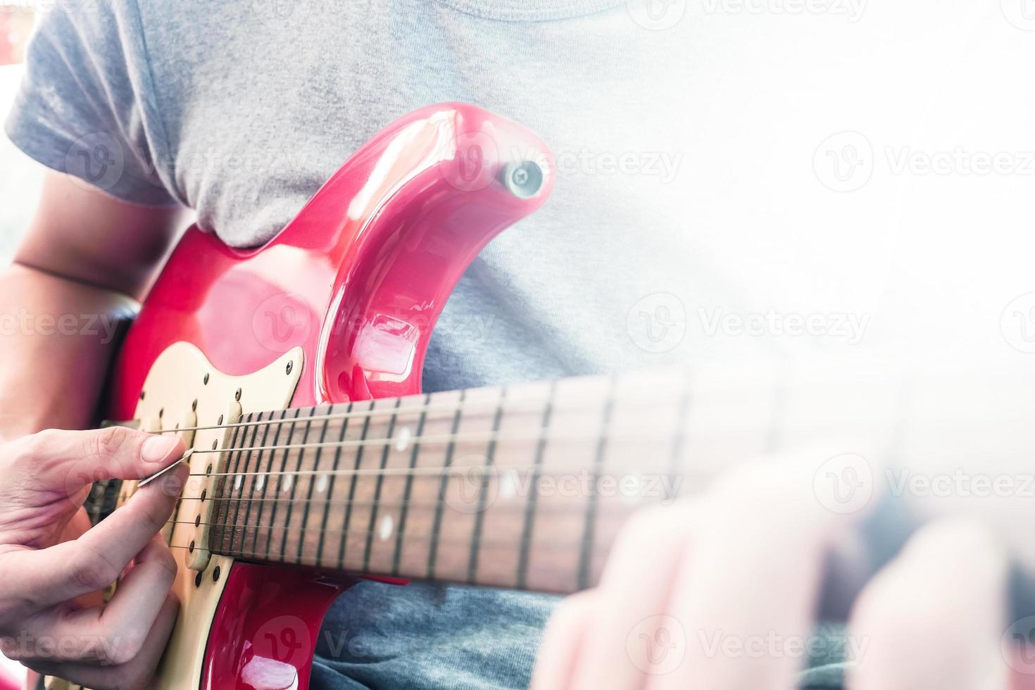 nahaufnahme männlicher hände, die e-gitarre spielen, flackern durch das sonnenlicht, selektiver fokus foto