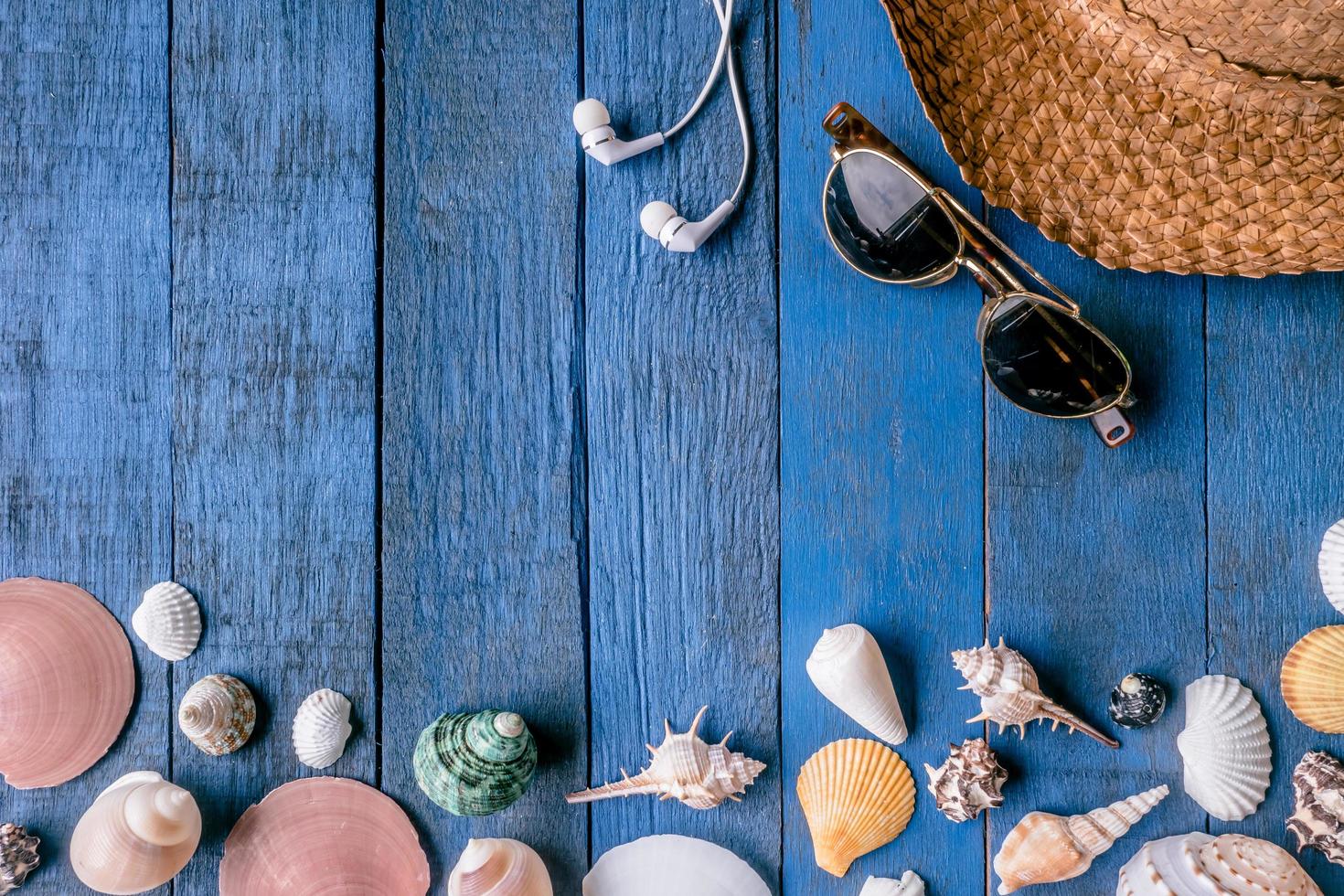 Draufsicht auf Zubehör für Sommerreise und Muscheln auf blau lackiertem Holzbretthintergrund. foto