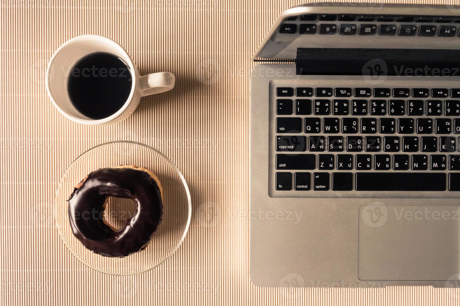 Draufsicht auf Laptop mit Kaffeetasse und Donut auf dem Tisch. foto