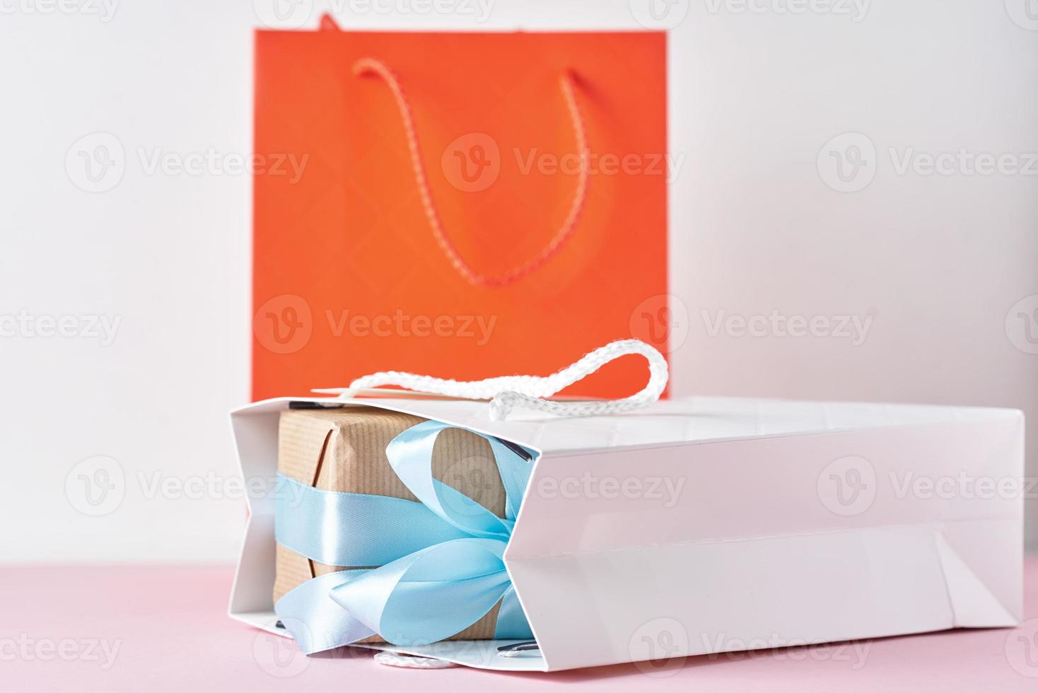 Papiereinkaufstasche mit Geschenkbox auf weißem Hintergrund foto