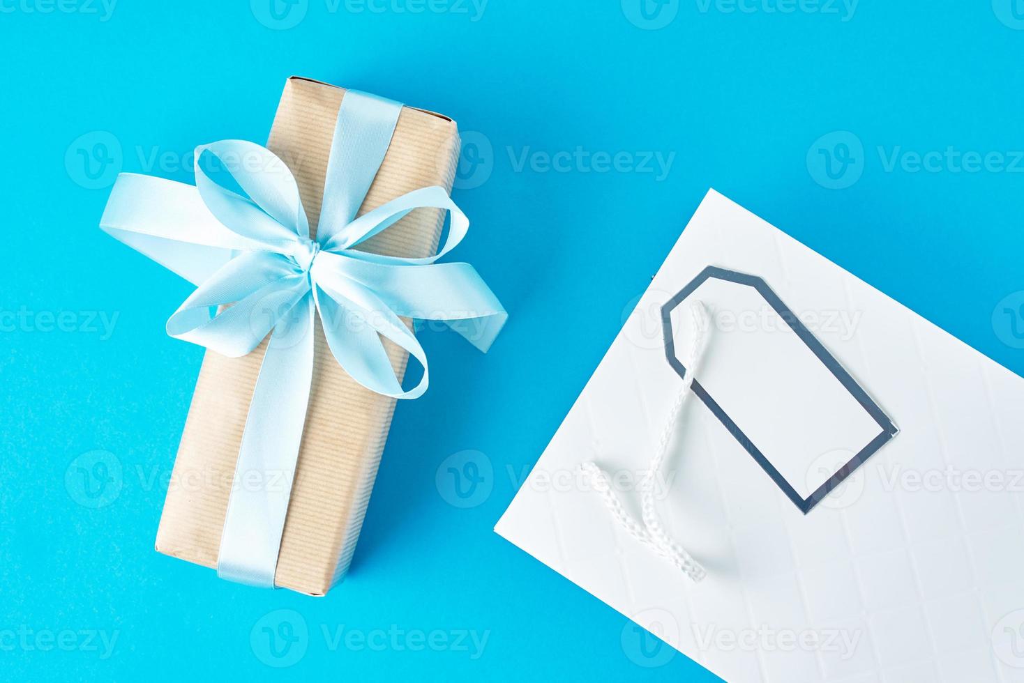 weiße einkaufstasche mit geschenkbox auf blauem hintergrund, draufsicht foto