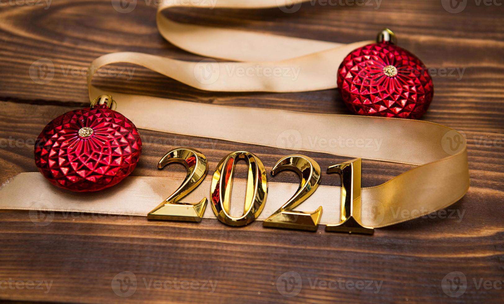 ein weihnachtsbaum aus goldband mit den zahlen 2021 ist mit roten luftballons auf dunklem holzhintergrund geschmückt. flach liegen. Platz für Text. neues jahr, weihnachtsmütze. foto