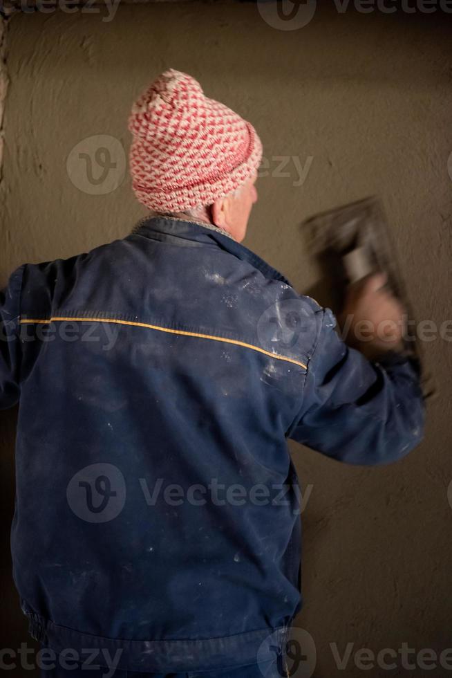 arbeiter, der die wand mit beton verputzt foto