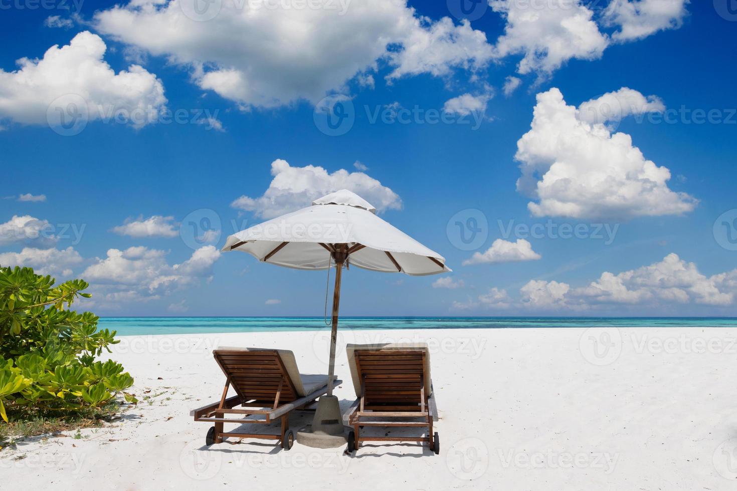 tropische Strandnatur als Sommerlandschaft mit Liegestühlen und Palmen und ruhigem Meer für Strandbanner. luxuriöse reiselandschaft, schönes ziel für urlaub oder urlaub. Strandszene foto