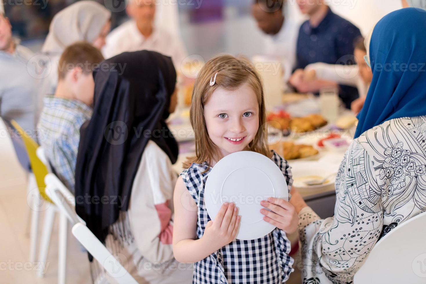 süßes kleines mädchen, das iftar-abendessen mit der familie genießt foto