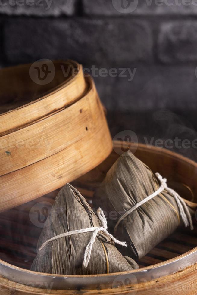 Reisknödel, Zongzi - chinesischer Reisknödel Zongzi auf schwarzem Backsteinhintergrund, Schiefertisch, Konzept des traditionellen Essens des Drachenbootfestivals, Nahaufnahme. foto