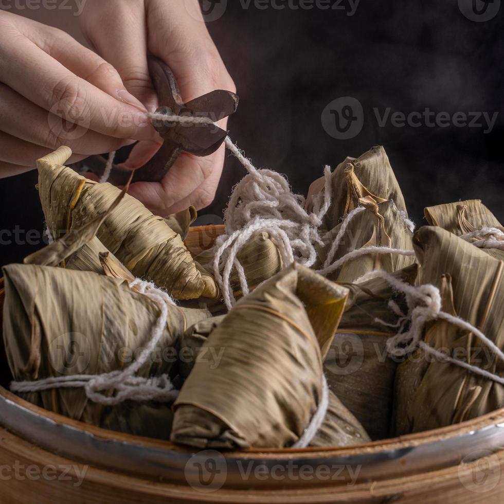 Reisknödel, Zongzi - Haufen chinesischer traditioneller gekochter Speisen auf Holztisch auf schwarzem Hintergrund, Konzept des Drachenbootfestivals, Nahaufnahme, Kopierraum foto