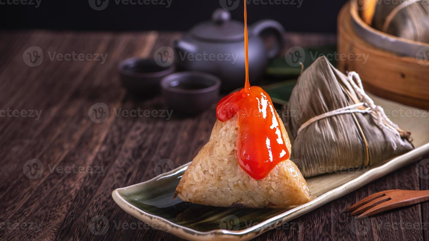 Reisknödel, Zongzi - Haufen chinesischer traditioneller gekochter Speisen auf Holztisch auf schwarzem Hintergrund, Konzept des Drachenbootfestivals, Nahaufnahme, Kopierraum foto