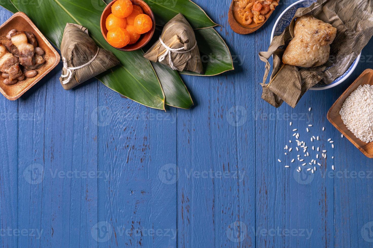 Konzept des Drachenbootfestivals - Reisknödel, Zongzi, traditionelles chinesisches Essen auf blauem Holzhintergrund für das Duanwu-Festival, Draufsicht, flaches Designkonzept. foto