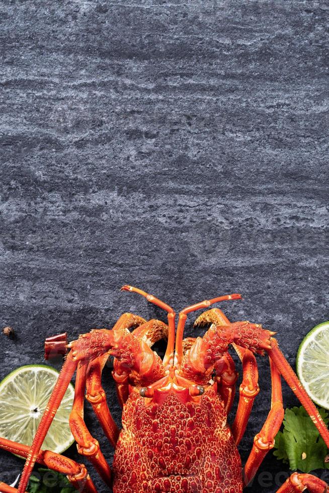 Gekochter gekochter Hummer, köstliches Abendessen mit Meeresfrüchten mit Messer und Gabel auf schwarzem Steinschieferhintergrund, Restaurantmenüdesign, Draufsicht, Overhead foto
