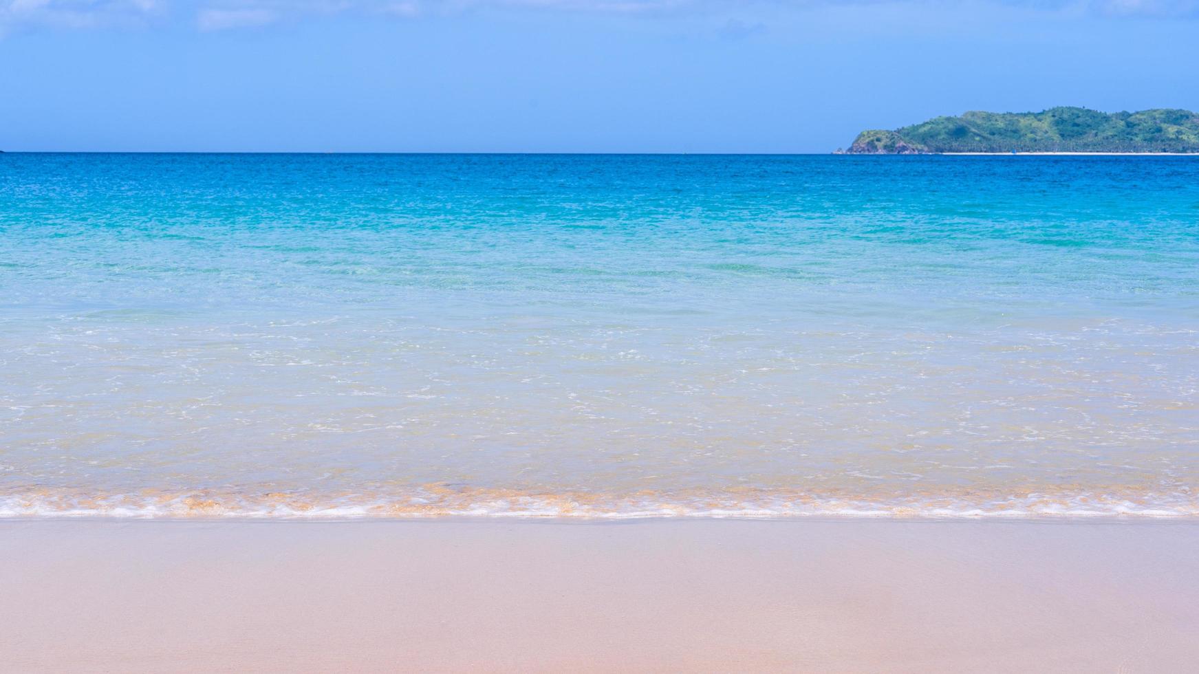 Wunderschöner, goldfarbener Sandstrand mit sanften Wellen, isoliert mit sonnigem blauem Himmel. konzept der tropischen ruhigen tourismusidee, kopierraum, nahaufnahme foto