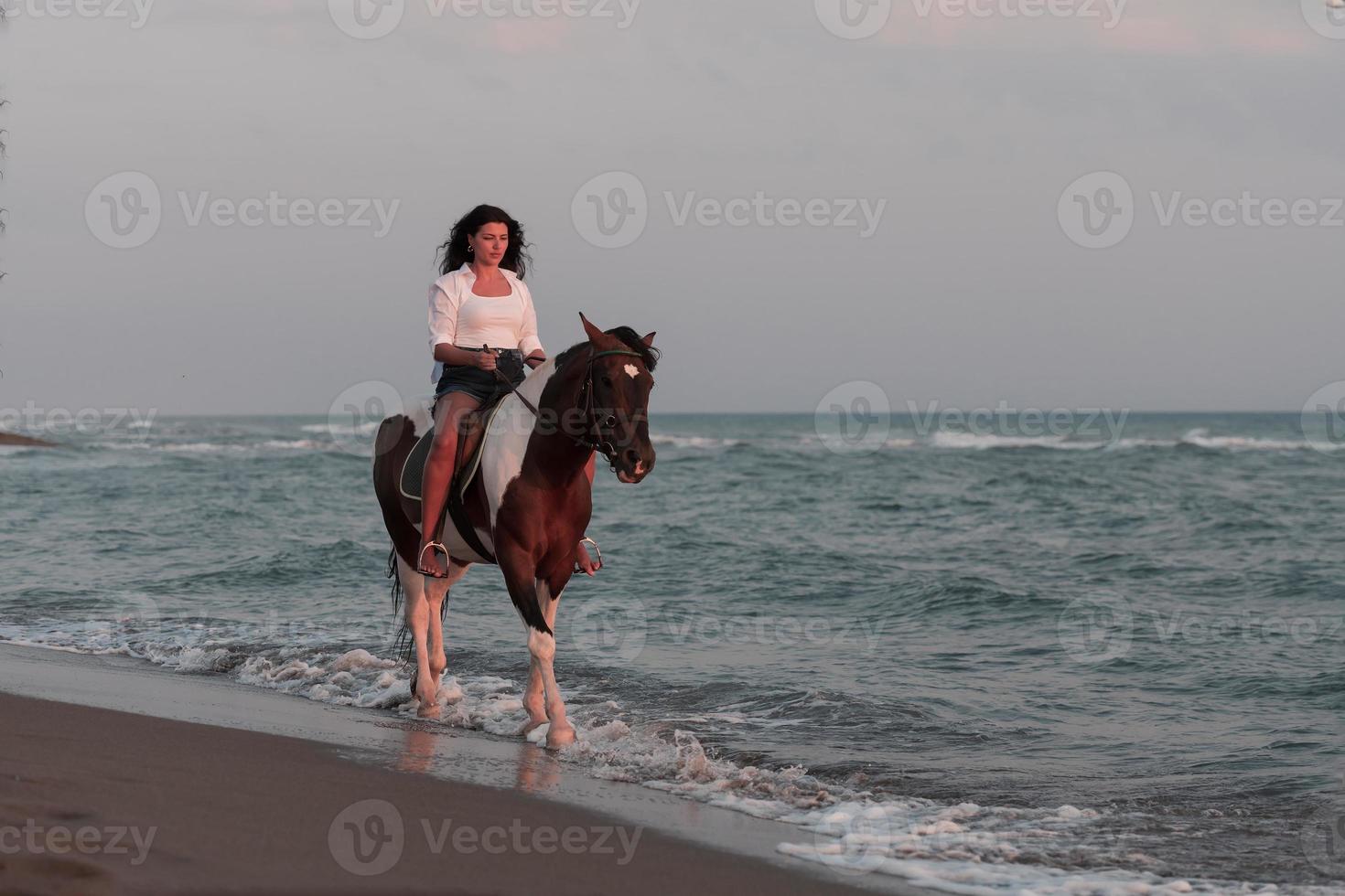 frau in sommerkleidung genießt es, bei sonnenuntergang an einem schönen sandstrand zu reiten. selektiver Fokus foto