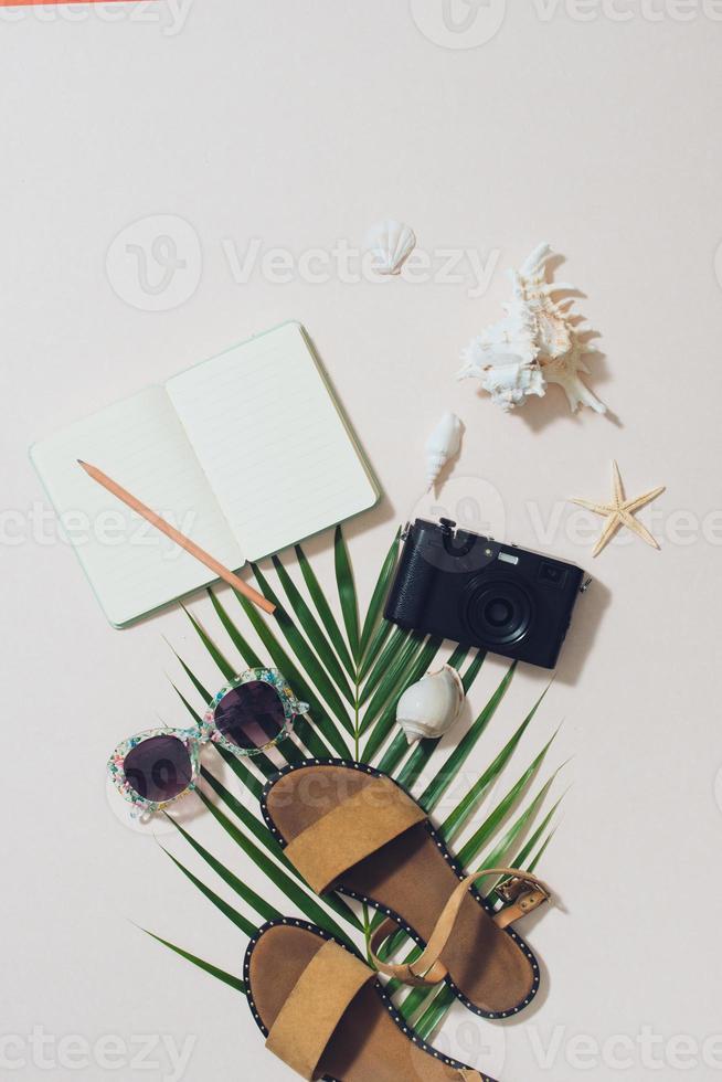 Bunte Sommerferienmode flach lag - Strohhut, Kamera, Sonnenbrille, Muscheln auf hellem Hintergrund foto