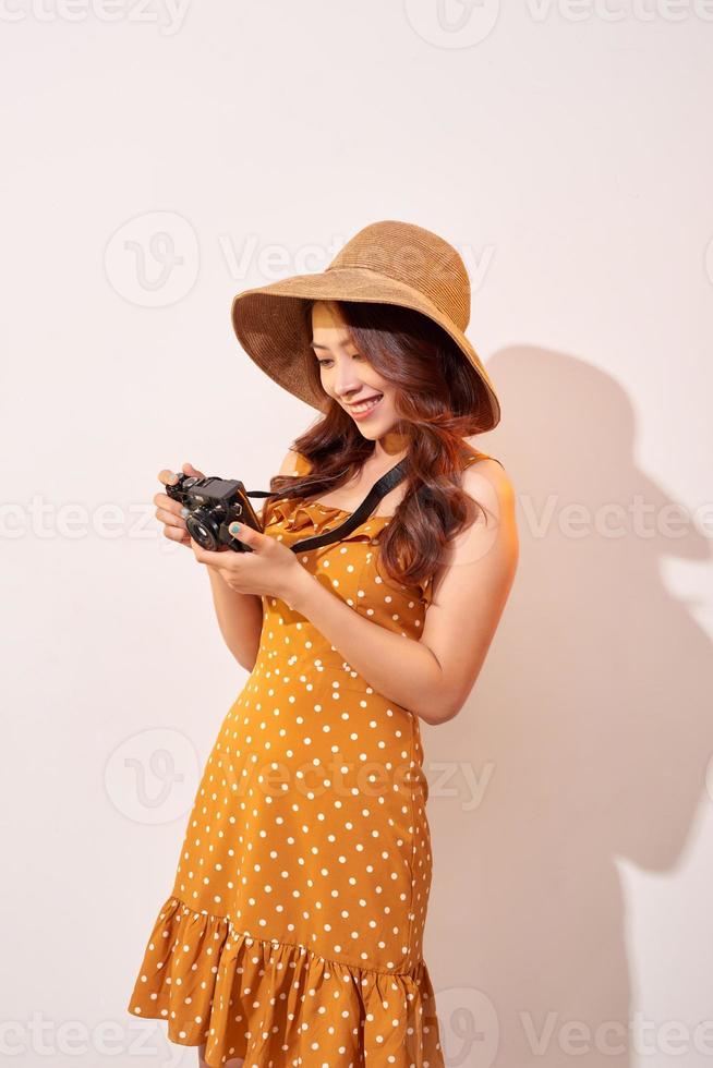 Bild einer jungen Fotografin, die über einer beigen Hintergrundwand isoliert ist, die eine Kamera hält. foto