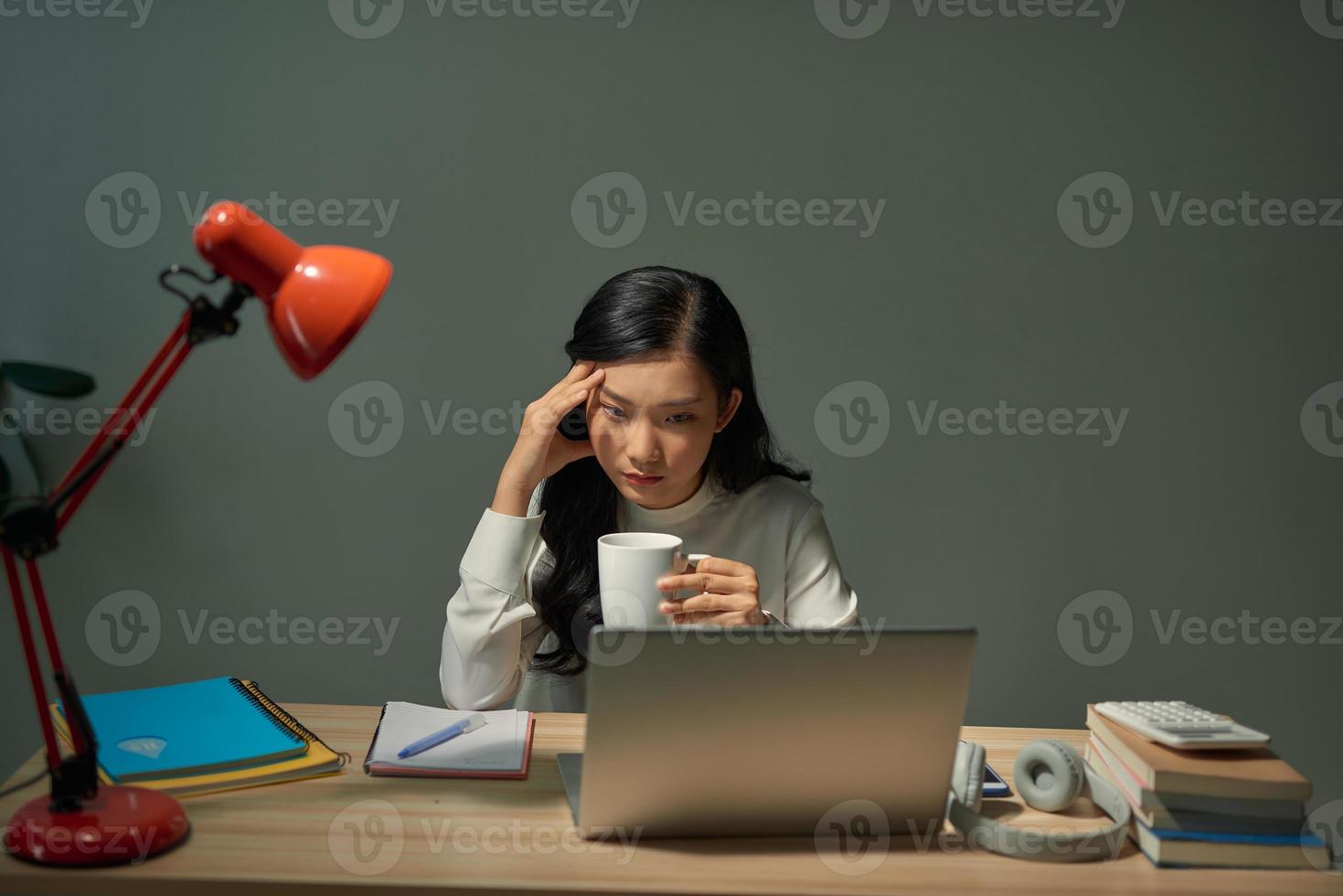 hübsche junge studentin, die am schreibtisch sitzt und ihre hausaufgaben macht, sie verbindet sich mit einem laptop mit dem internet foto