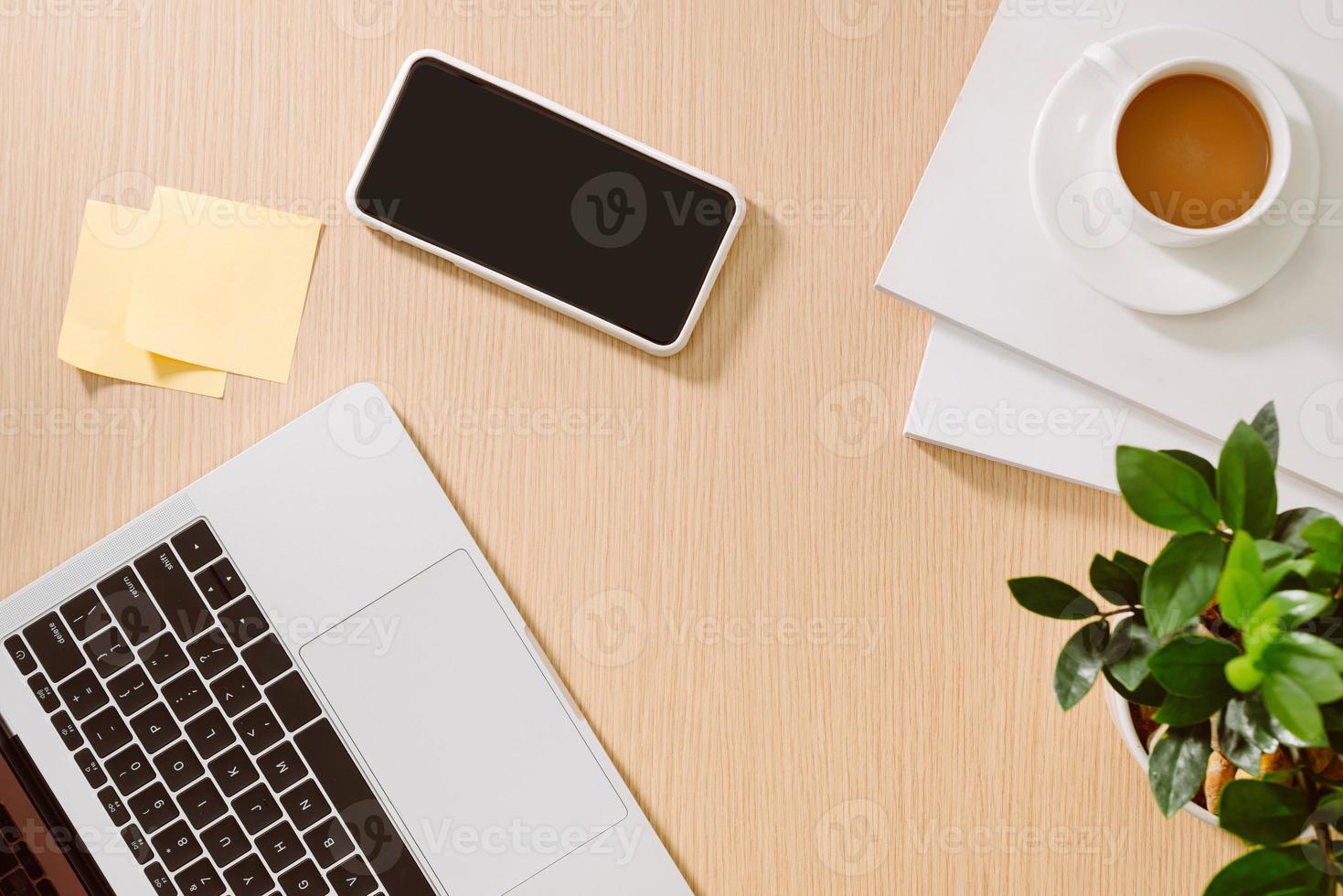 trendiger femininer Arbeitsplatz für das Home Office. weißer Schreibtisch. laptop, kaffeetasse und telefon, notizbuch, bleistift. flache Lage, Draufsicht, Kopierbereich foto