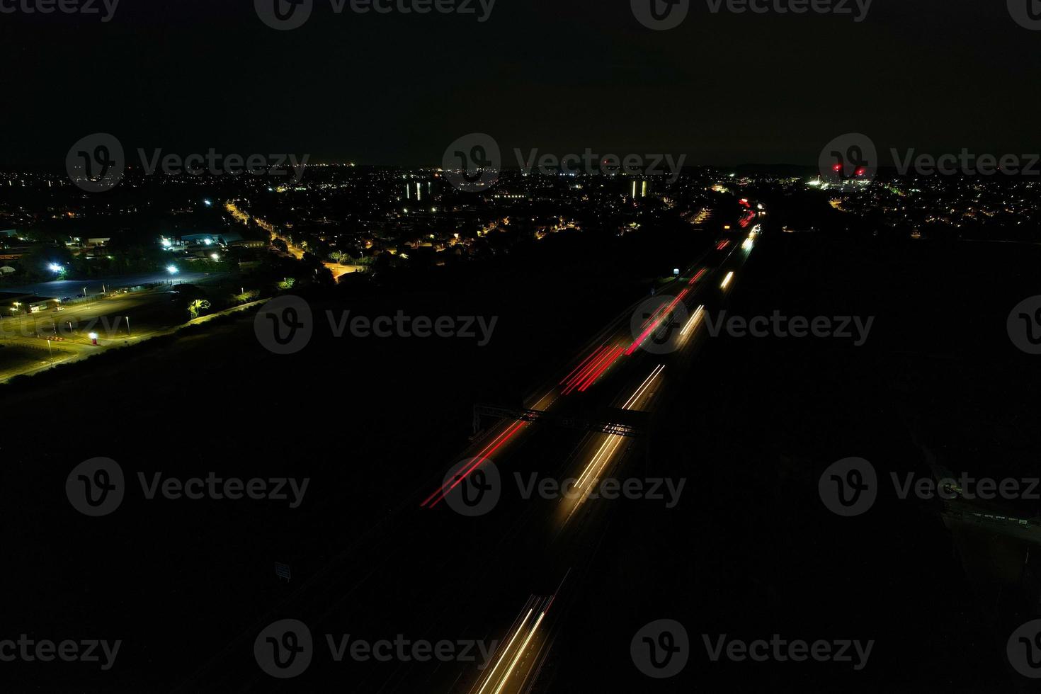 Nachtluftaufnahme der britischen Autobahnen mit beleuchteten Straßen und Verkehr. Aufnahmen von Autobahnen, die mit der Drohnenkamera über Milton Keynes und Autobahnen von England in dunkler Nacht aufgenommen wurden foto