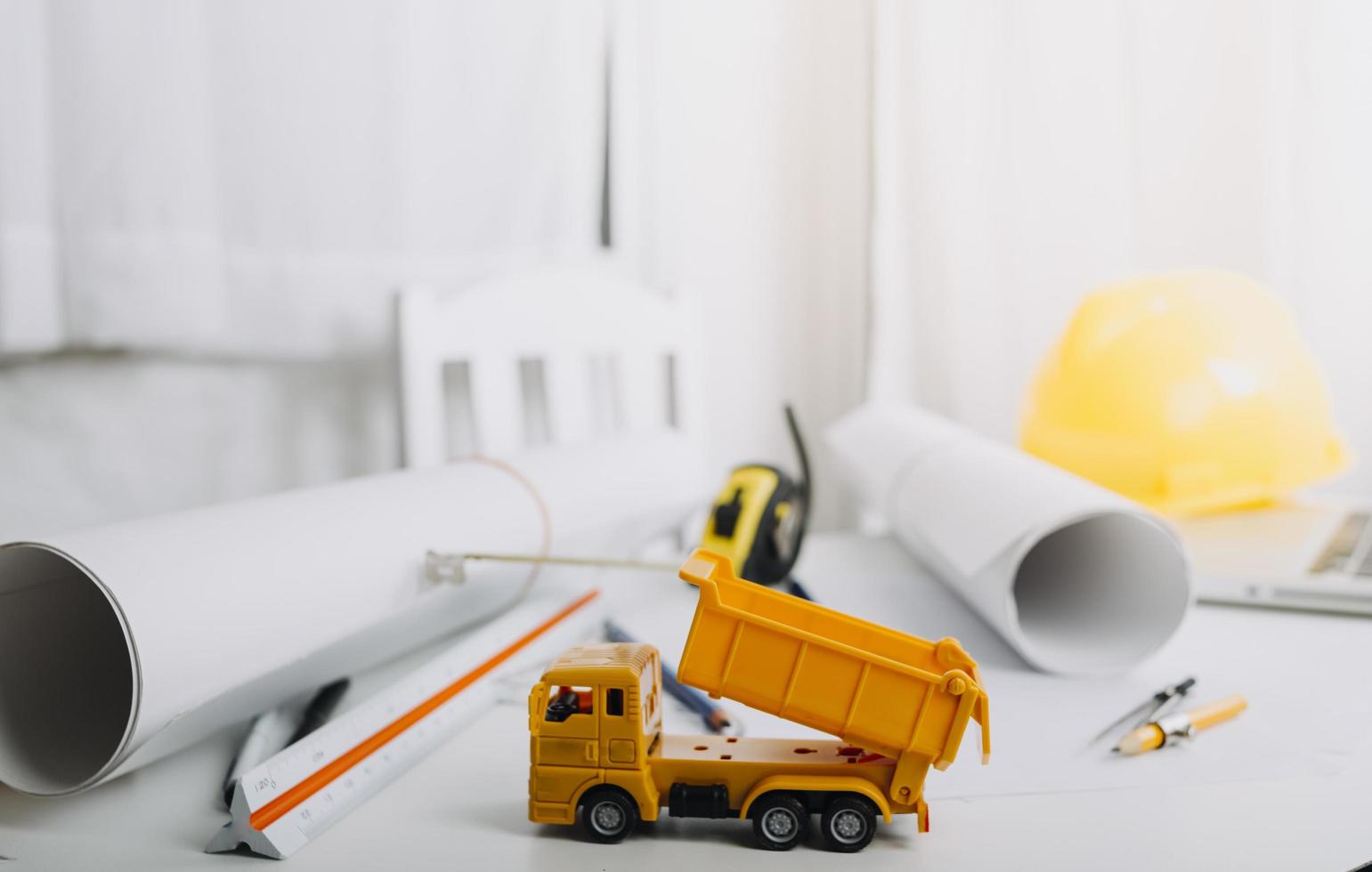 Zwei Kollegen diskutieren über Datenverarbeitung und Tablet, Laptop mit einem Architekturprojekt auf der Baustelle am Schreibtisch im Büro foto