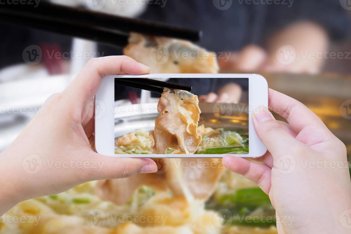 frau, die foto von sukiyaki shabu shabu macht