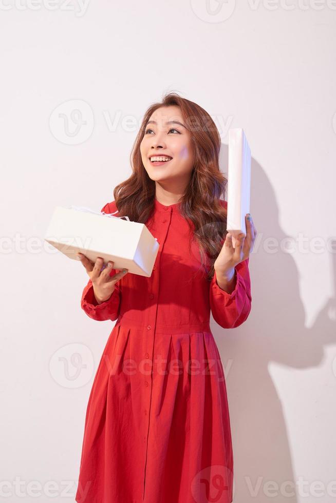Porträt eines glücklichen lächelnden Mädchens, das eine Geschenkbox öffnet, die über weißem Hintergrund getrennt wird foto