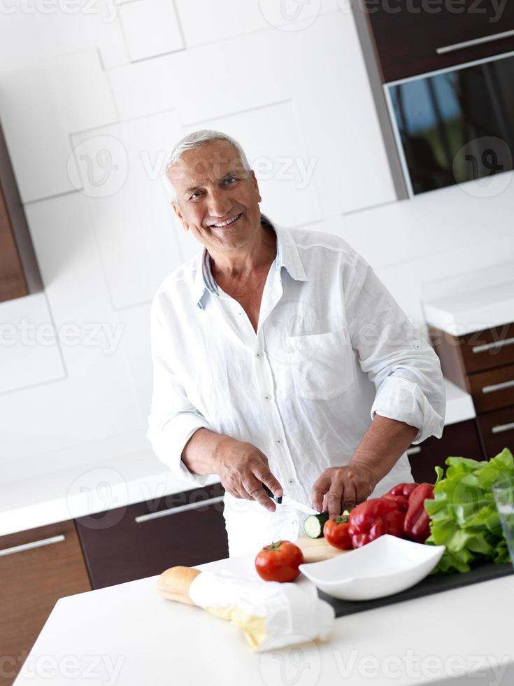 Mann kocht zu Hause und bereitet Salat in der Küche zu foto