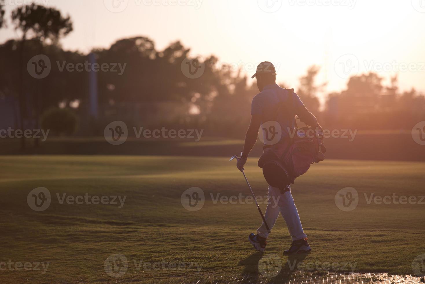 golfer, der bei schönem sonnenuntergang golftasche geht und trägt foto