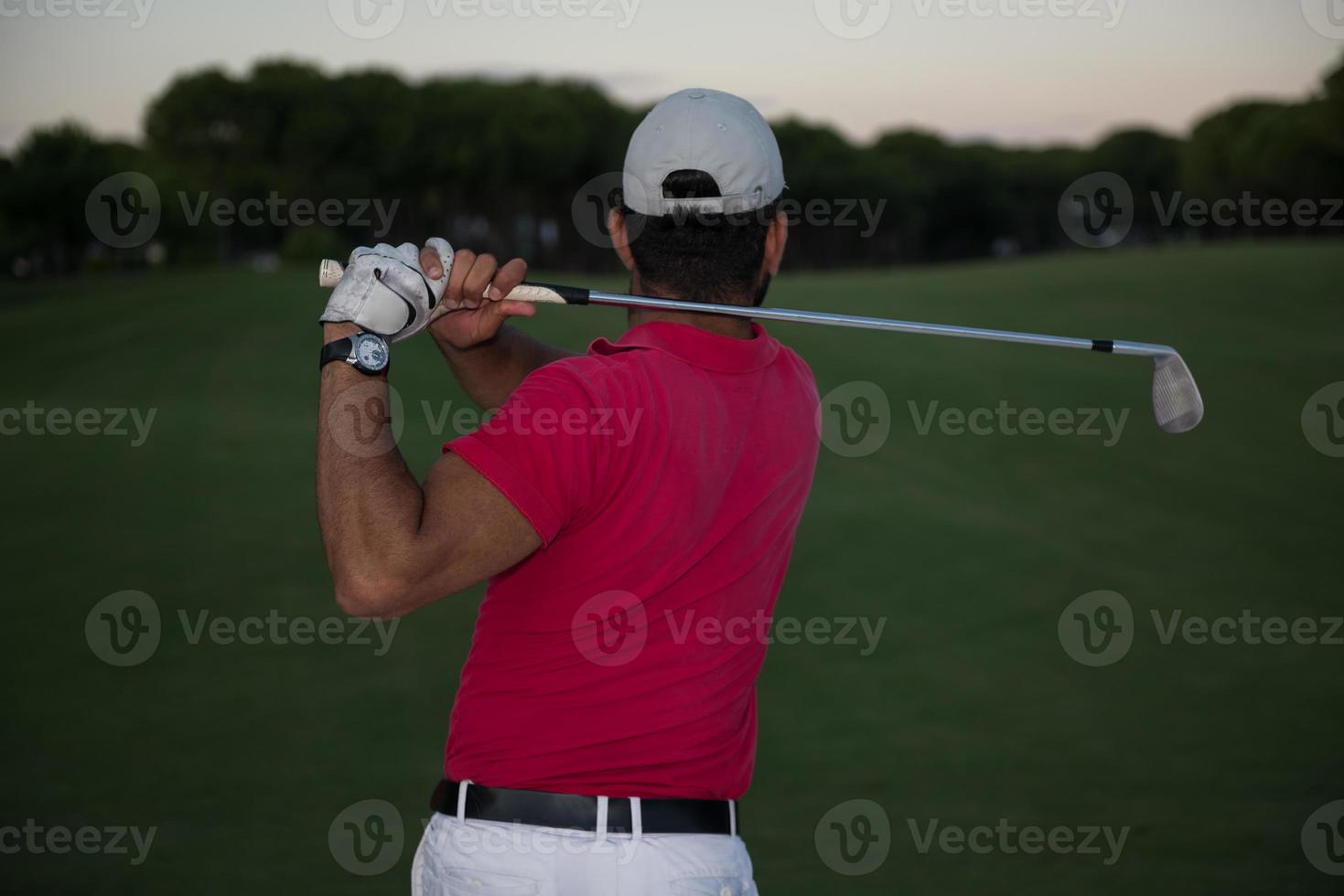 Golfspieler, der einen Sandbunker schlägt, der bei Sonnenuntergang erschossen wird foto