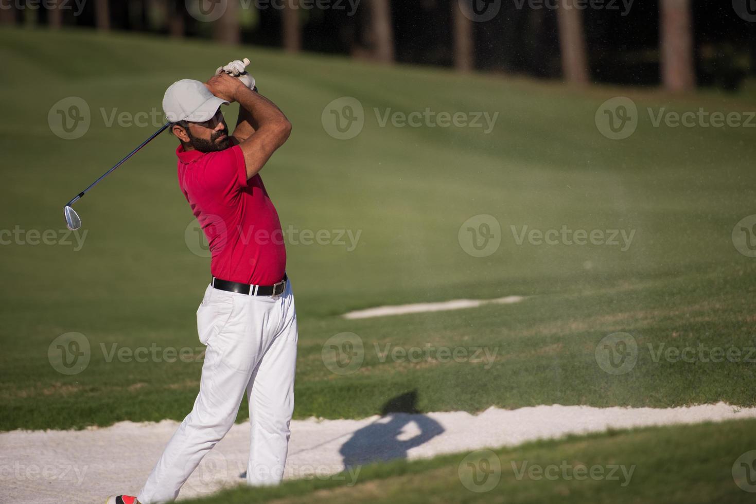 Golfspieler, der einen Sandbunkerschlag schlägt foto