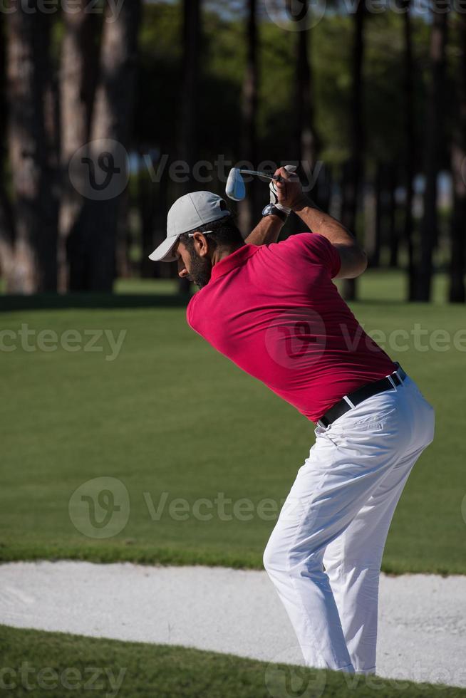 Golfspieler, der einen Sandbunkerschlag schlägt foto