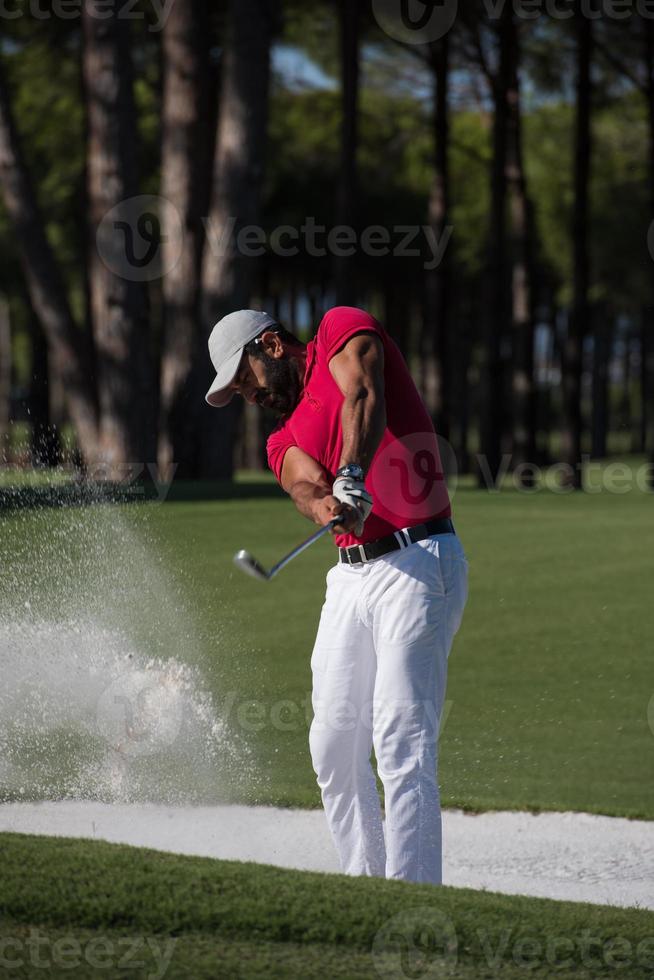 Golfspieler, der einen Sandbunkerschlag schlägt foto