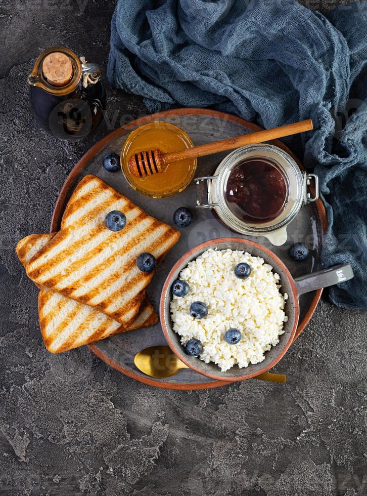 köstlicher Hüttenkäse mit Blaubeere, Honig, Erdbeermarmelade und Toast. gesundes Frühstück. Ansicht von oben foto