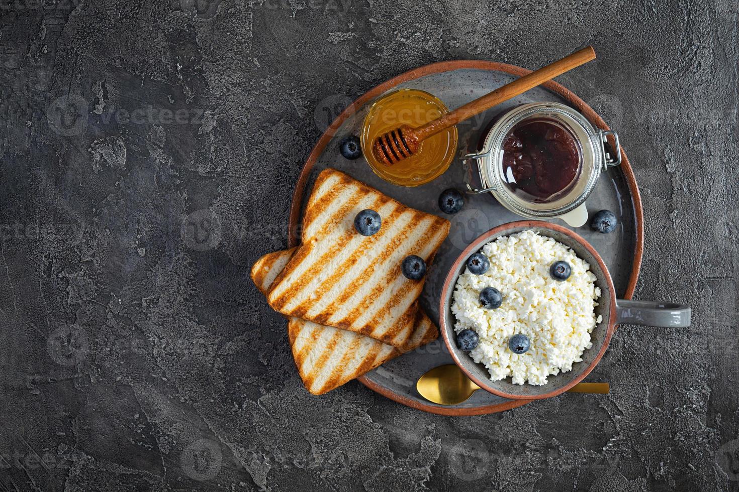 köstlicher Hüttenkäse mit Blaubeere, Honig, Erdbeermarmelade und Toast. gesundes Frühstück. Ansicht von oben foto