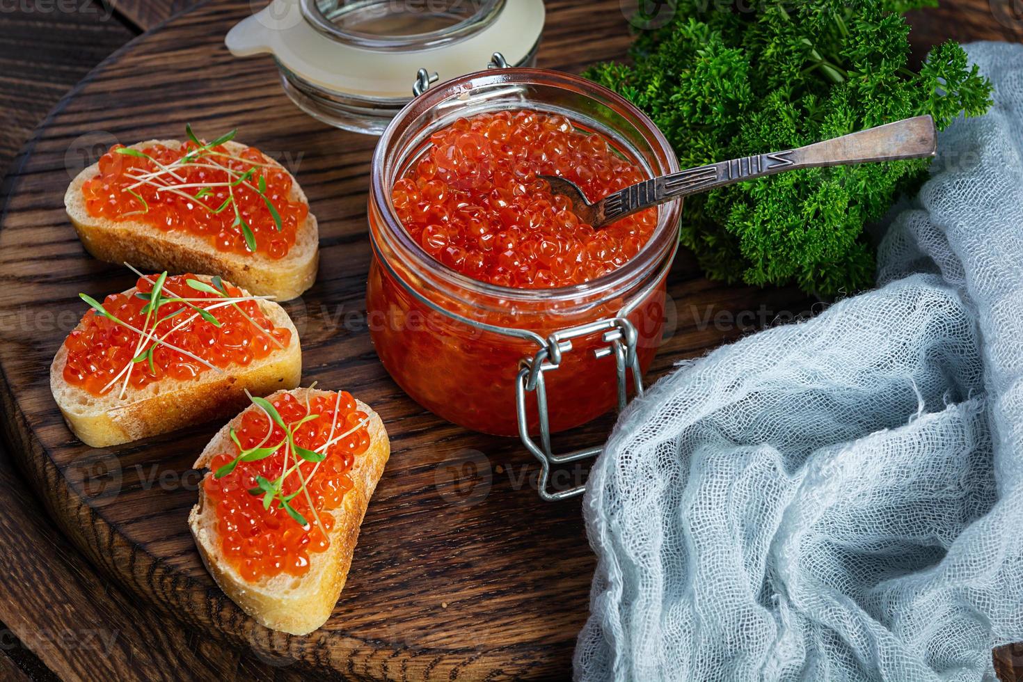Köstlicher frischer roter Kaviar mit Baguette-Toast auf Holzhintergrund foto