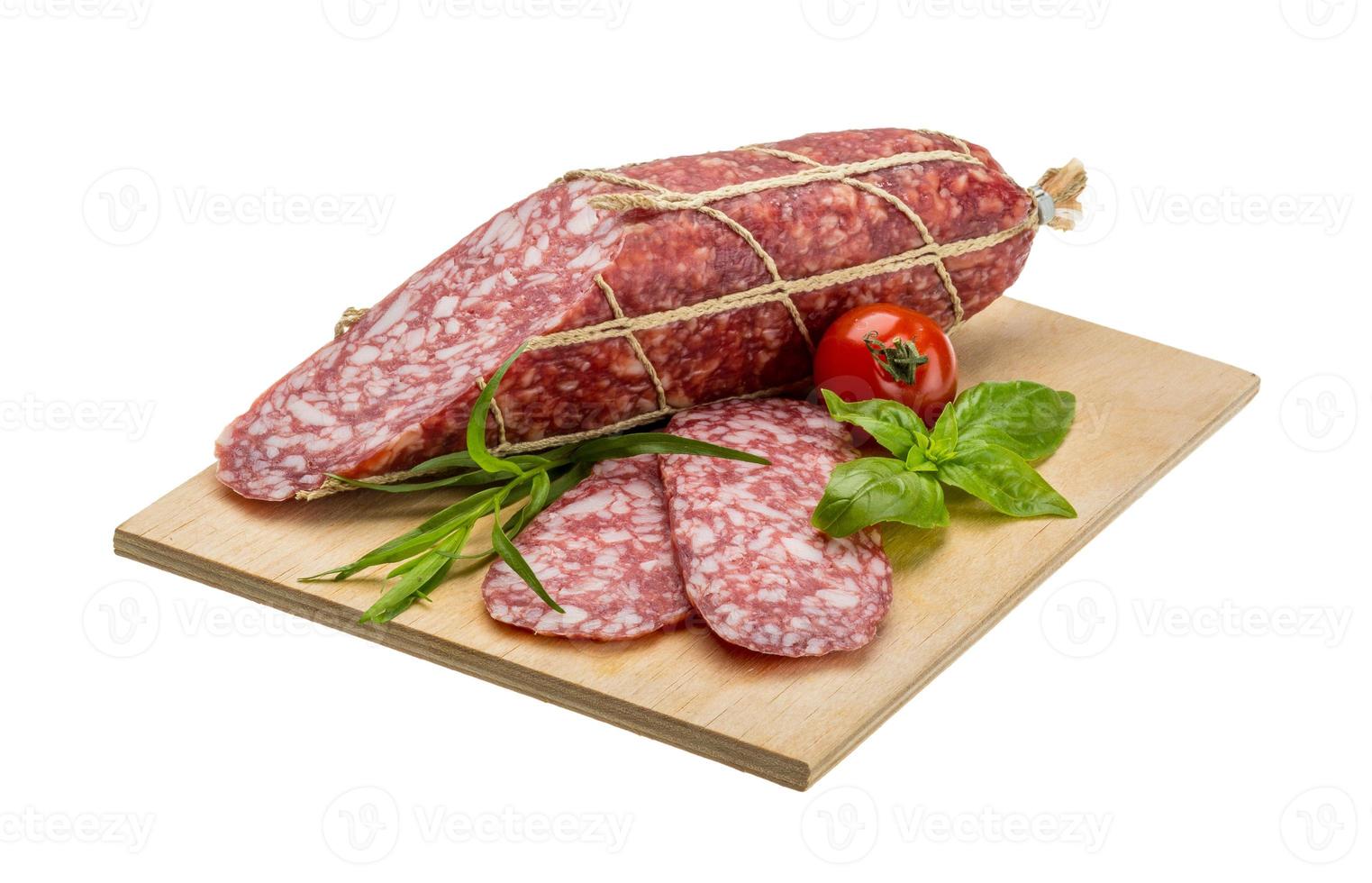 Salami auf Holzplatte und weißem Hintergrund foto