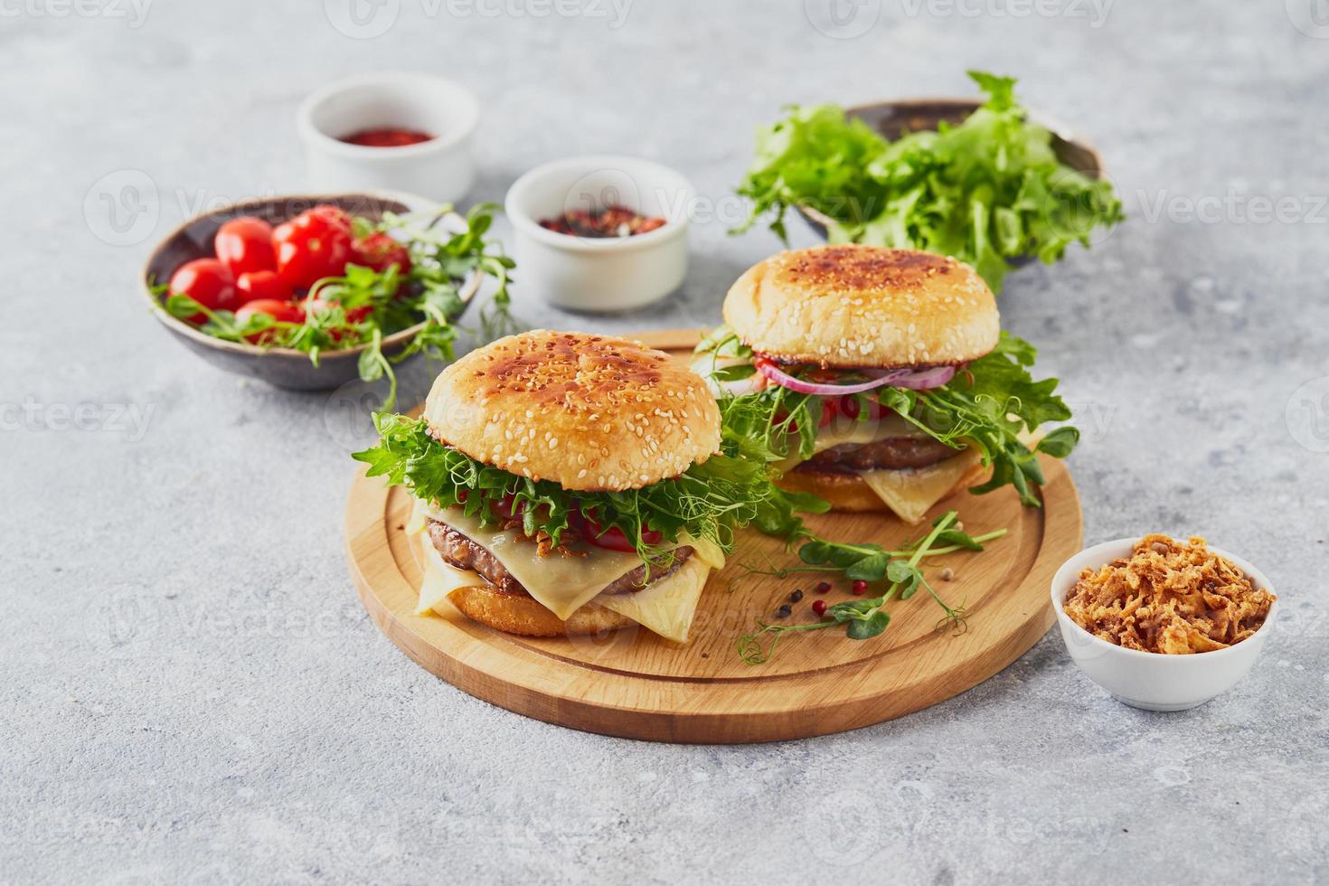 zwei Burger mit Kalbsschnitzel und Kräutern auf Holzbrett foto