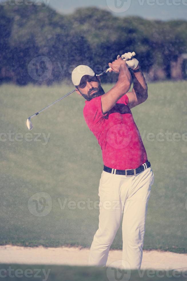 Golfspieler, der einen Sandbunkerschlag schlägt foto