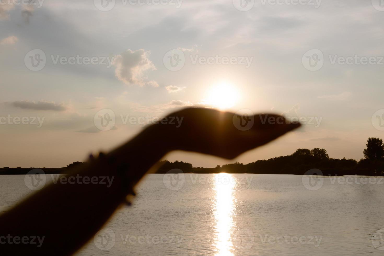 Nahaufnahme einer Frau, die bei Sonnenuntergang die Sonne in der Hand hält. foto