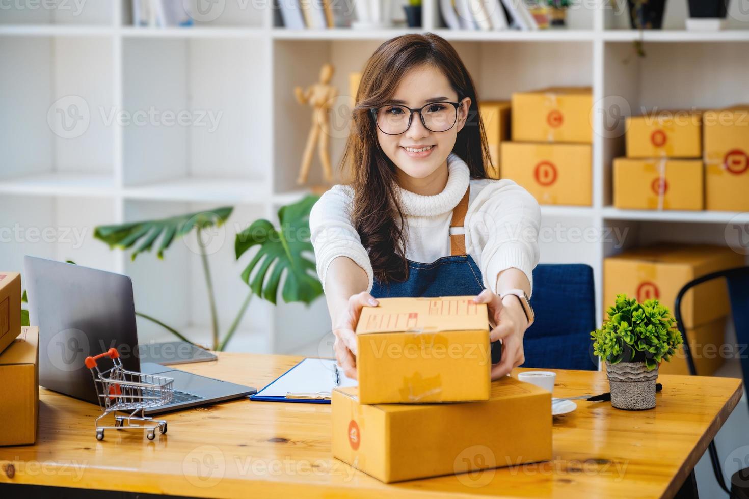 Geschäftsinhaber holt Paketboxen ab und prüft Online-Bestellungen am Computer, um die Verpackung vorzubereiten. Produkte verpacken, um sie an Kunden zu versenden. foto