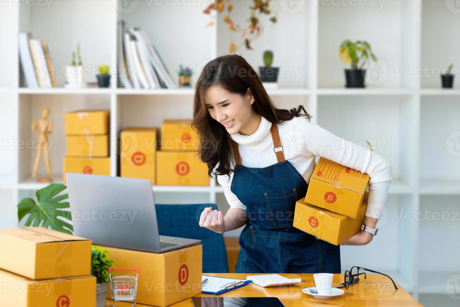 Von zuhause aus arbeiten. glückliche frauen, die produkte online verkaufen, gründen einen kleinunternehmer, indem sie mit einem laptop die preise berechnen und sich auf den versand vorbereiten. foto