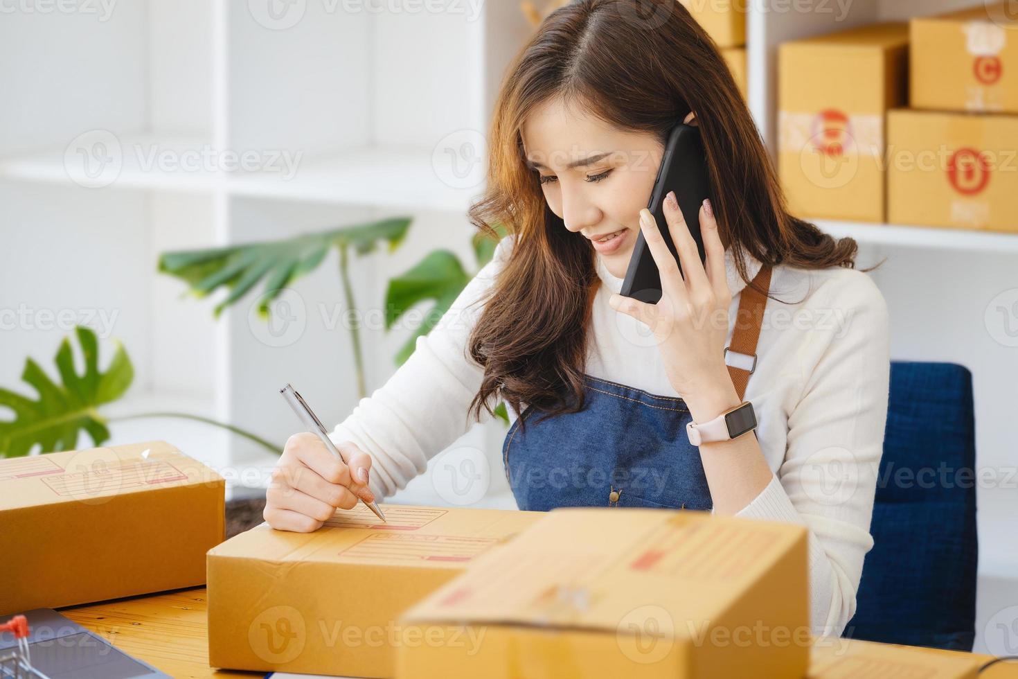 Von zuhause aus arbeiten. glückliche frauen, die produkte online verkaufen, gründen einen kleinunternehmer, indem sie mit smartphone und laptop preise berechnen und sich auf den versand vorbereiten. foto