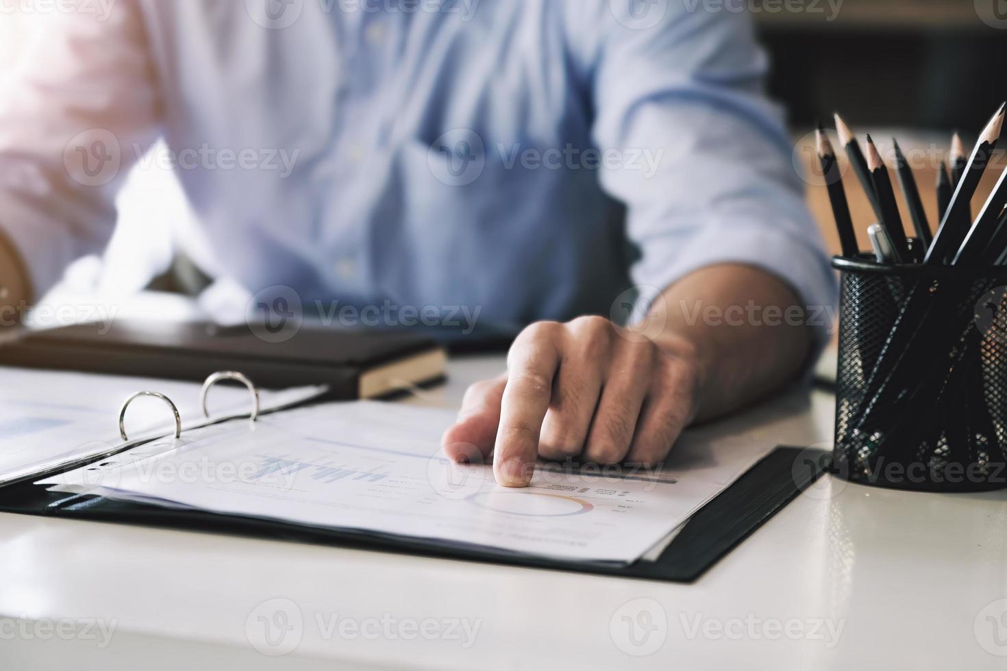 Bei der Prüfung des Finanzplans zeigt ein Wirtschaftsprüfer auf eine Akte, in der er den unregelmäßigen Finanzplan des Unternehmens zusammenfasst. foto