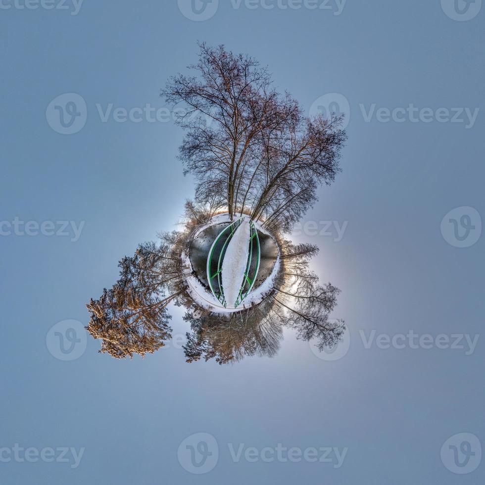 Winziger Winterplanet im schneebedeckten Wald auf Holzbrücke. Transformation des sphärischen Panoramas 360 Grad. sphärische abstrakte Luftaufnahme im Wald. Krümmung des Raumes. foto