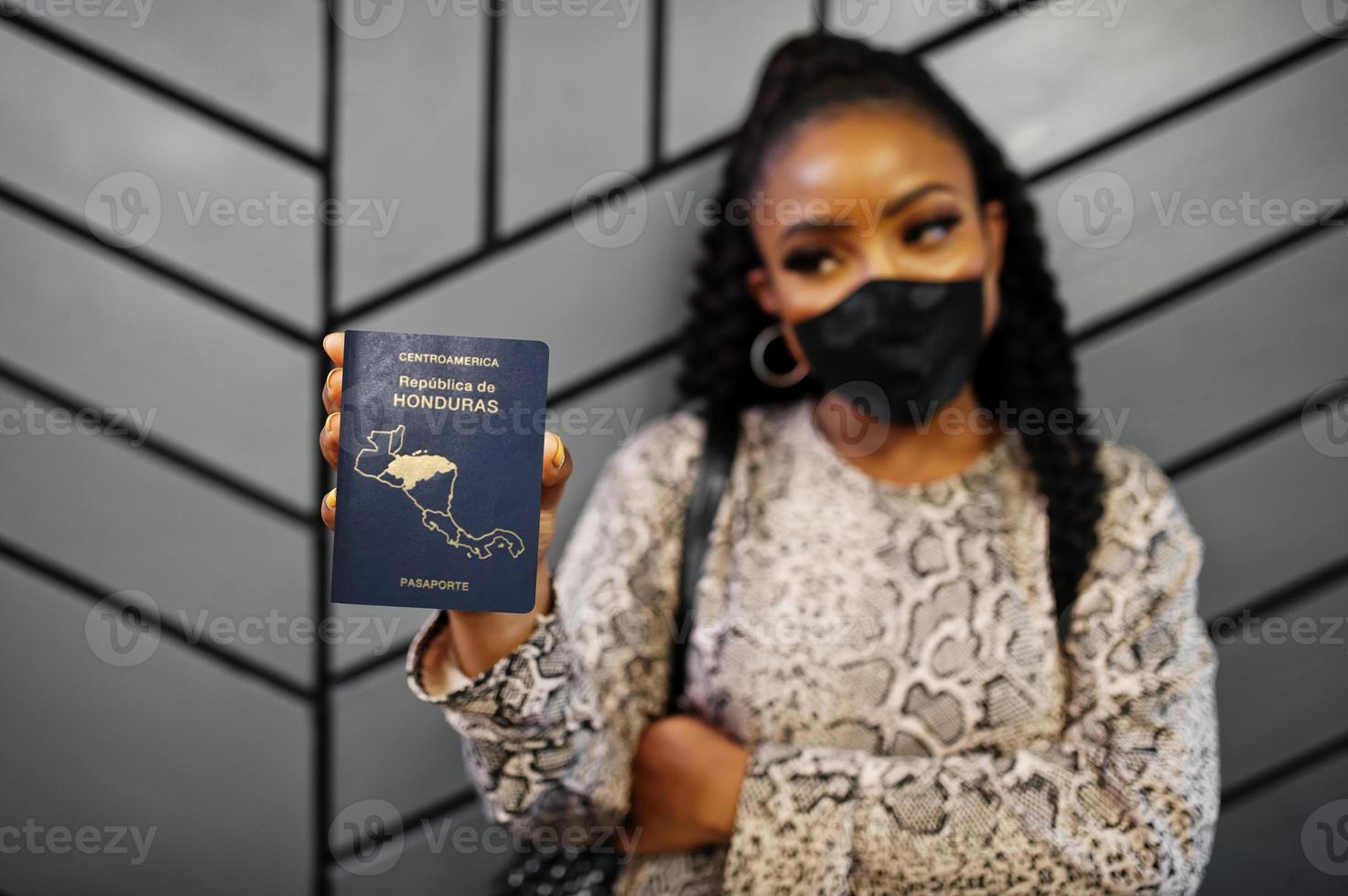 Afroamerikanerin mit schwarzer Gesichtsmaske zeigt Honduras-Pass in der Hand. coronavirus im amerikanischen land, grenzschließung und quarantäne, virusausbruchskonzept. foto